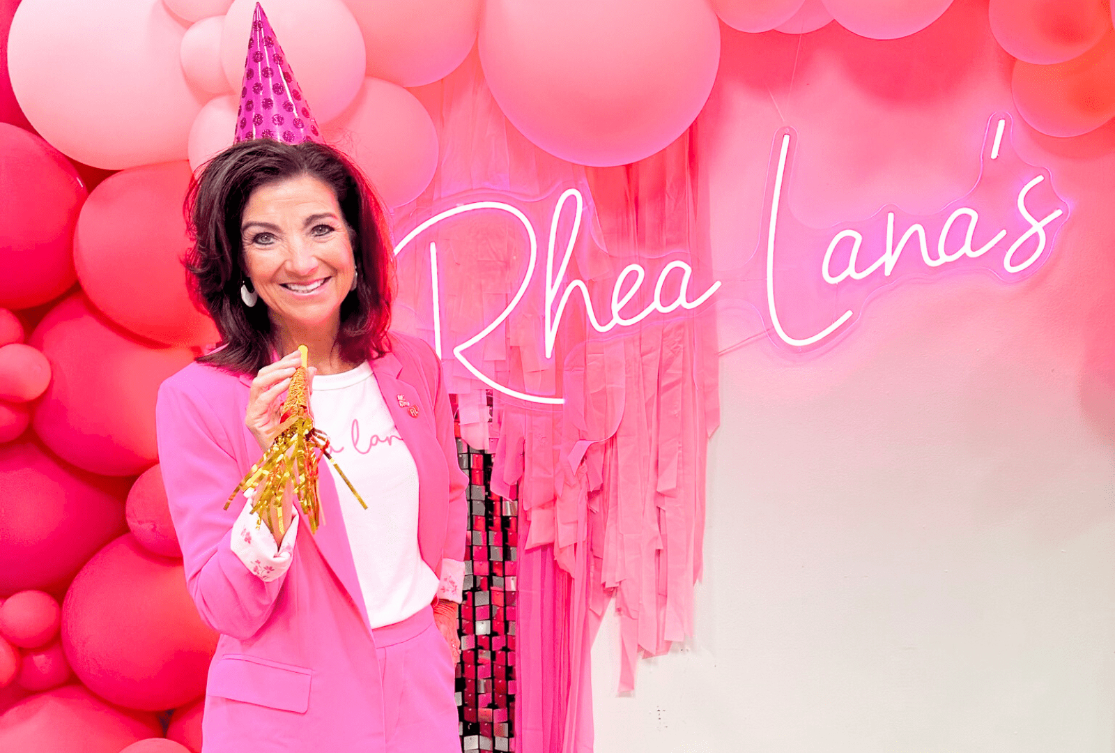 Rhea Lana in a party hat in front of balloons and Rhea Lana's sign